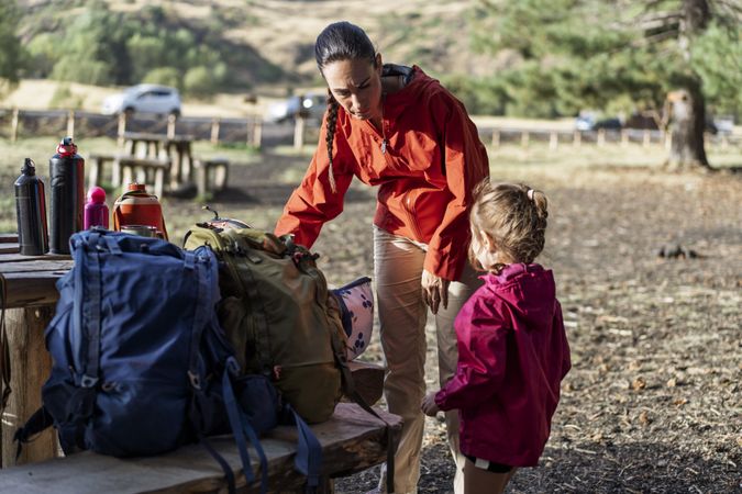 Mother and daughter preparing for hike in campsite before forest adventure