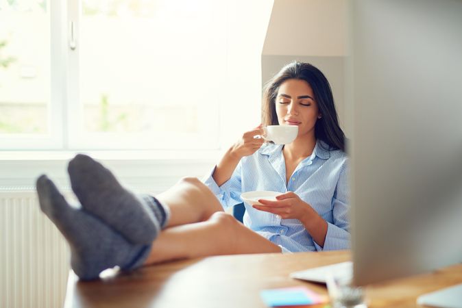 Arab woman sitting at her desk with feet up sipping tea