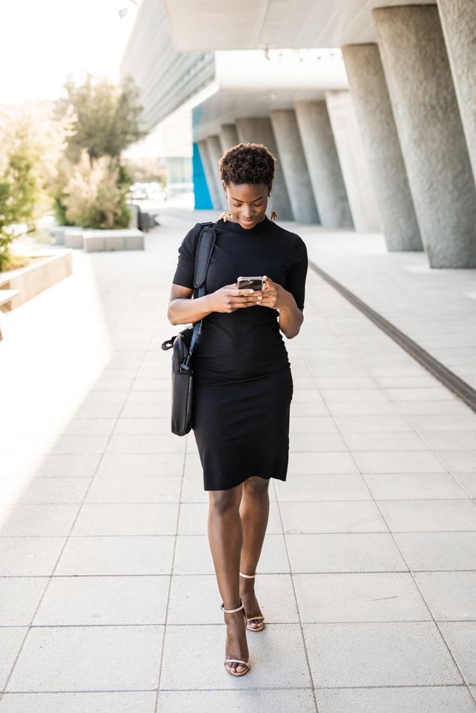 Concentrated female using mobile near urban building
