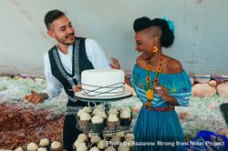 Bride and groom laughing behind wedding cake 4BaRM5