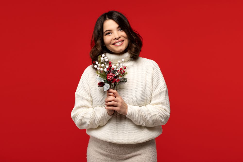 Smiling woman in sweater holds festive bouquet