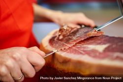 Close up of woman’s hands in butcher shop slicing ham 47BxO5