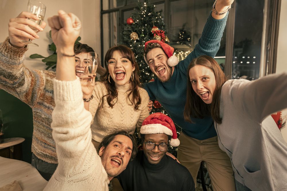 A happy group of diverse friends taking a joyful selfie at a Christmas party.