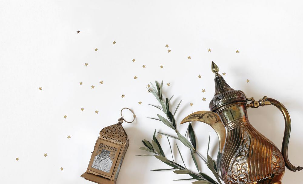 Arabic dallah coffee pot, golden ornamental Moroccan lantern and green olive tree branches