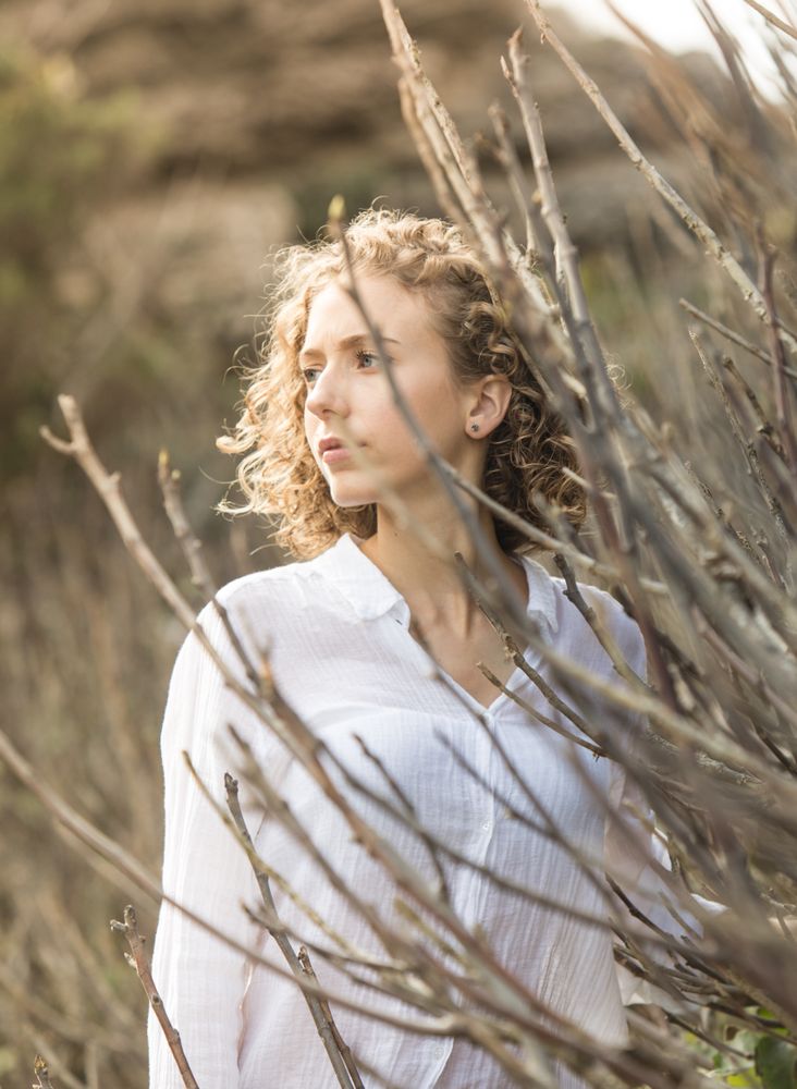 Young woman near dry twigs of bushes