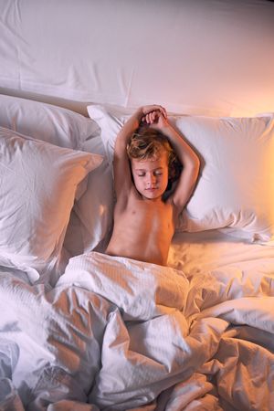 Shirtless boy sleeping on bed