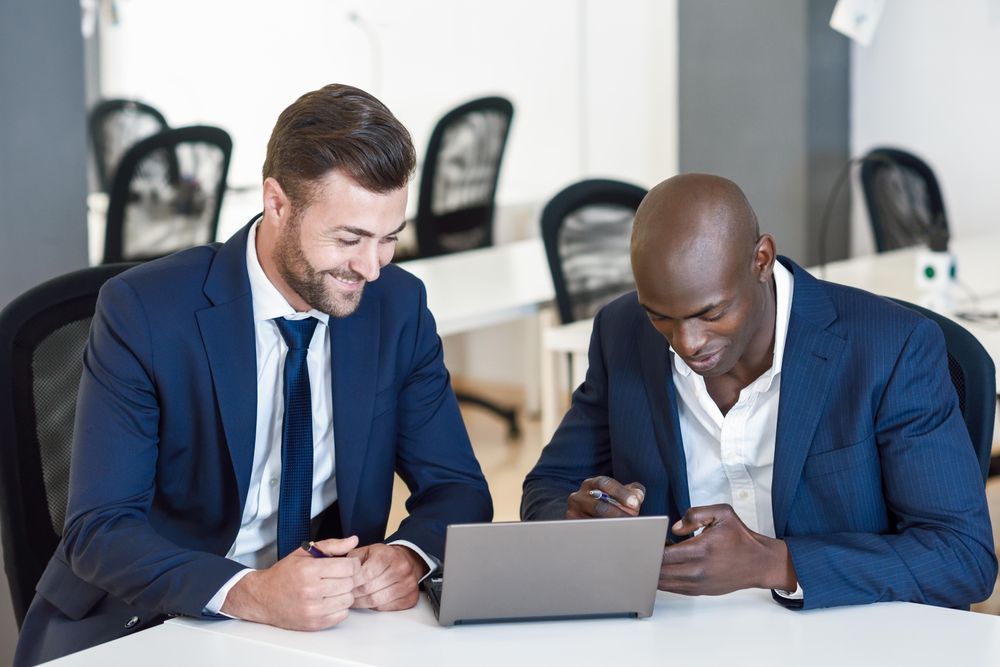 Two men wearing blue suits working in a bright office