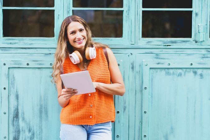 Woman leaning against blue wall with digital tablet