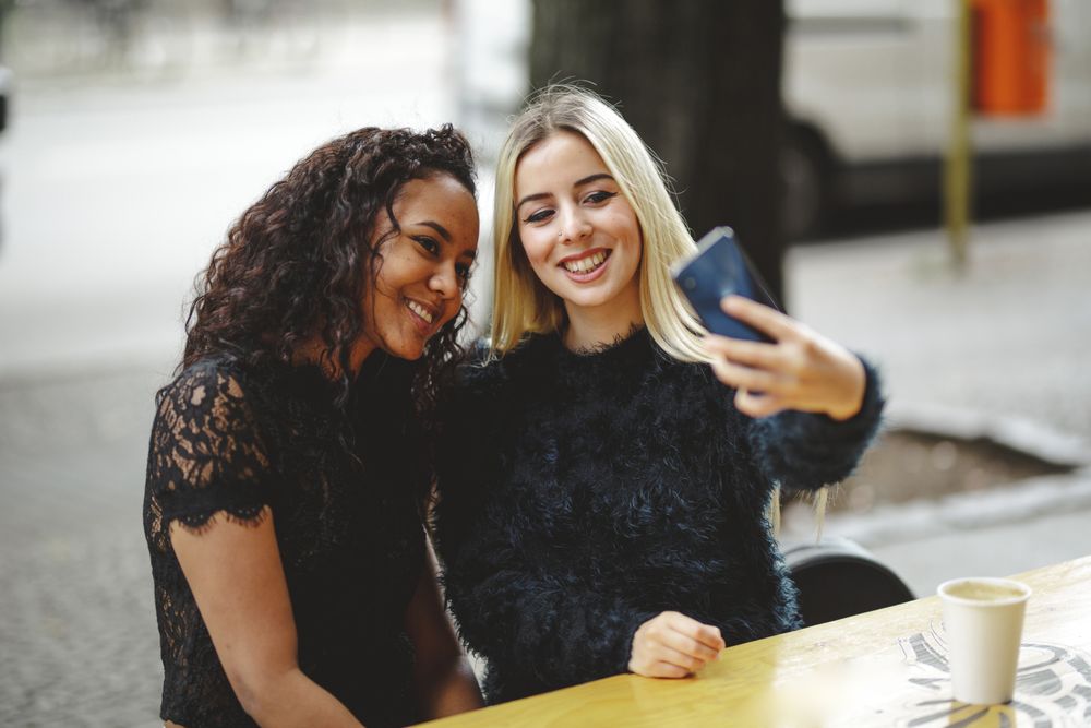 Friends taking selfie in street cafe
