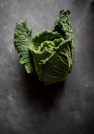Woman holding fresh cabbage on table
