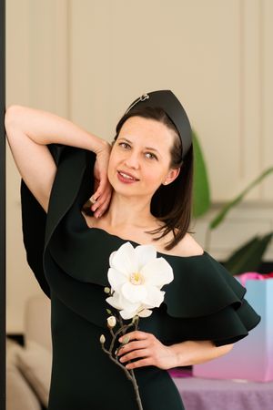 Woman posing with flower, smiling at birthday party.