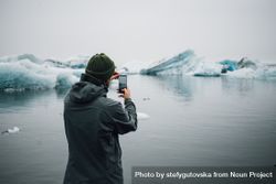 Man taking picture of glacier with smart phone on overcast day 4jaMJ5