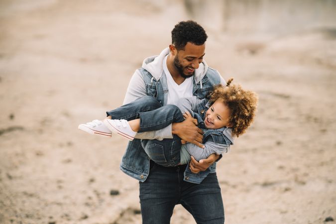 Black father playing with child on ground