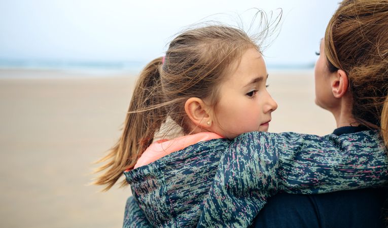 Back view of mother and daughter looking at sea