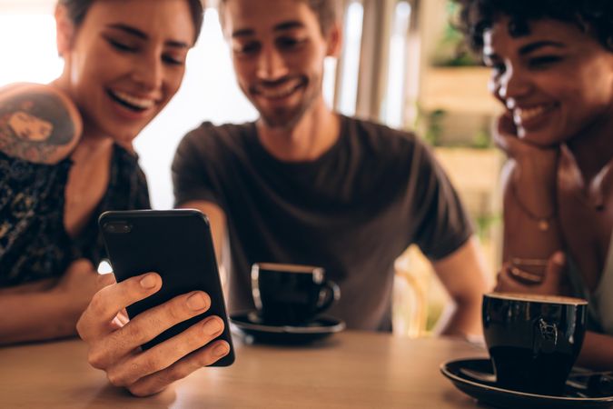 Friends having fun using a smart phone in cafe