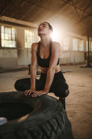 Tired woman after training in the gym sitting by a tire
