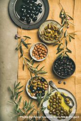 Olives in bowls with branches, on beige table linen, vertical composition 5nQeZ0