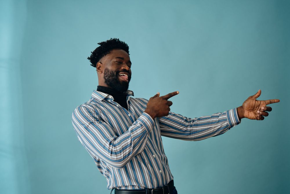Joking Black man pointing with both hands to something to the side