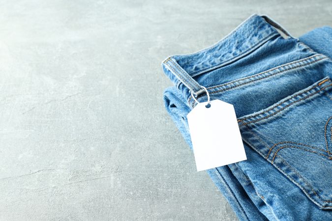 Folded jeans with a tag on a light background