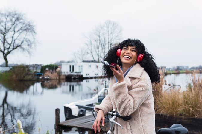 Cheerful Black woman listening to music in park