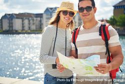 Smiling couple standing near river with map 5XDkP5