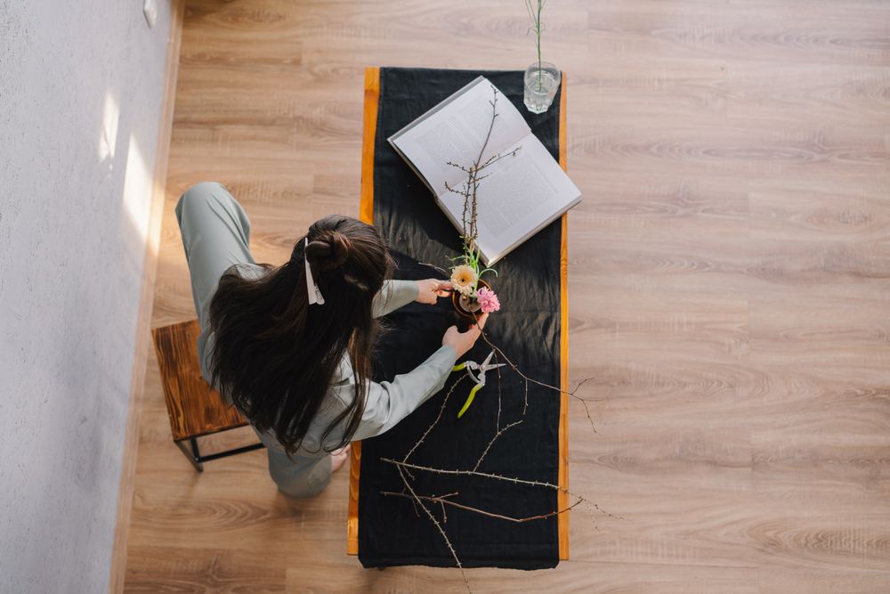 Top view of woman decorating a table with an open book and flowers