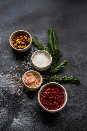 Top view of salt and seasoning bowls and rosemary on kitchen counter