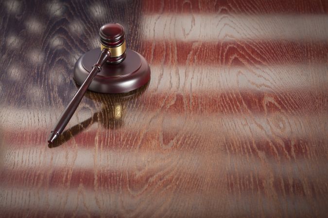 Wooden Gavel Resting on Flag Reflecting Table