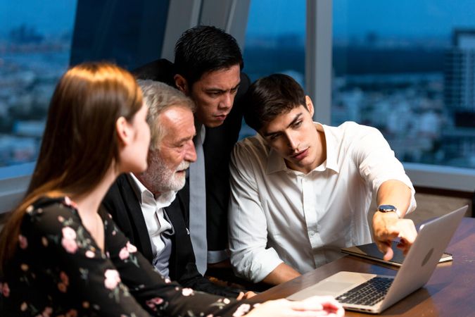 Male employee presenting work from laptop to colleagues in meeting room