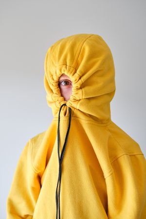 Anonymous child in hoodie against gray wall