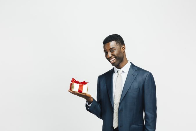 Excited man in a suit holding golden gift