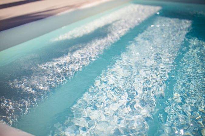 Summer relax and recreational concept, blue ripped water with stairs in swimming pool, sunny blurry waves