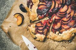 Whole fruit tart on parchment paper, with knife, close up