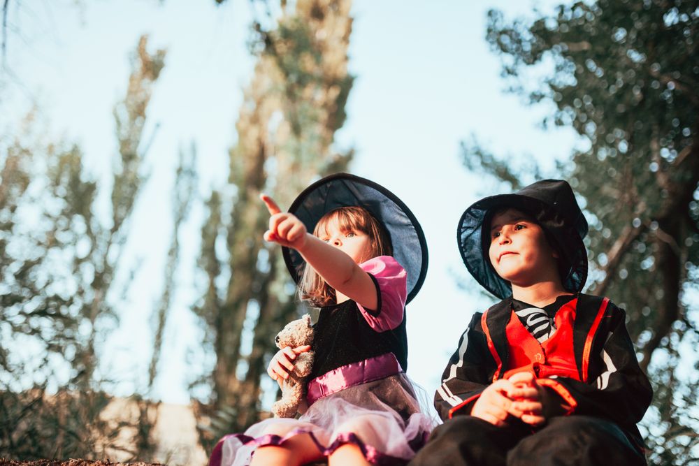 Brother and sister sitting down in halloween costumes