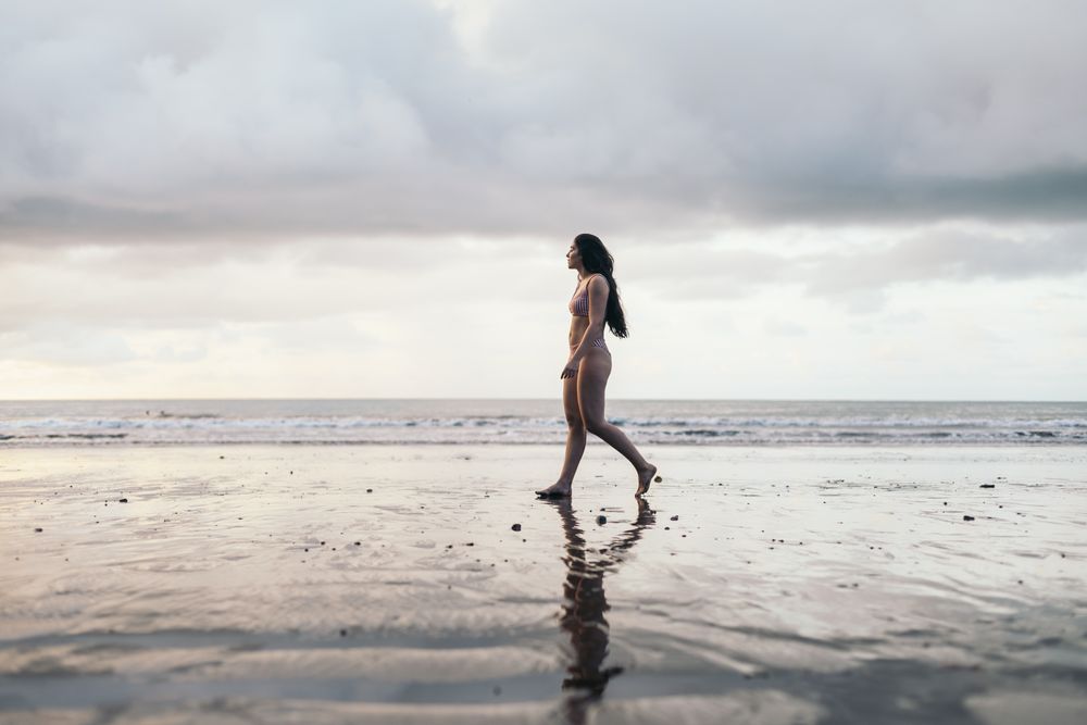 Brunette woman in bikini walking on the beach