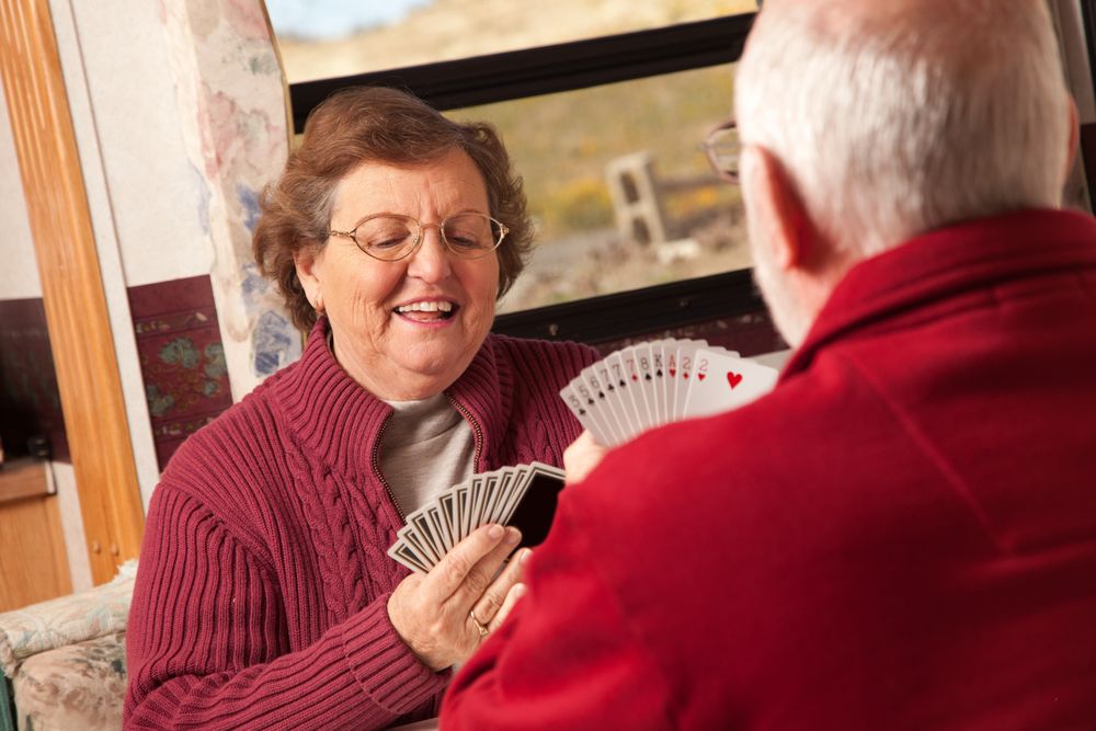 Happy Adult Couple Playing Cards in Their Trailer RV