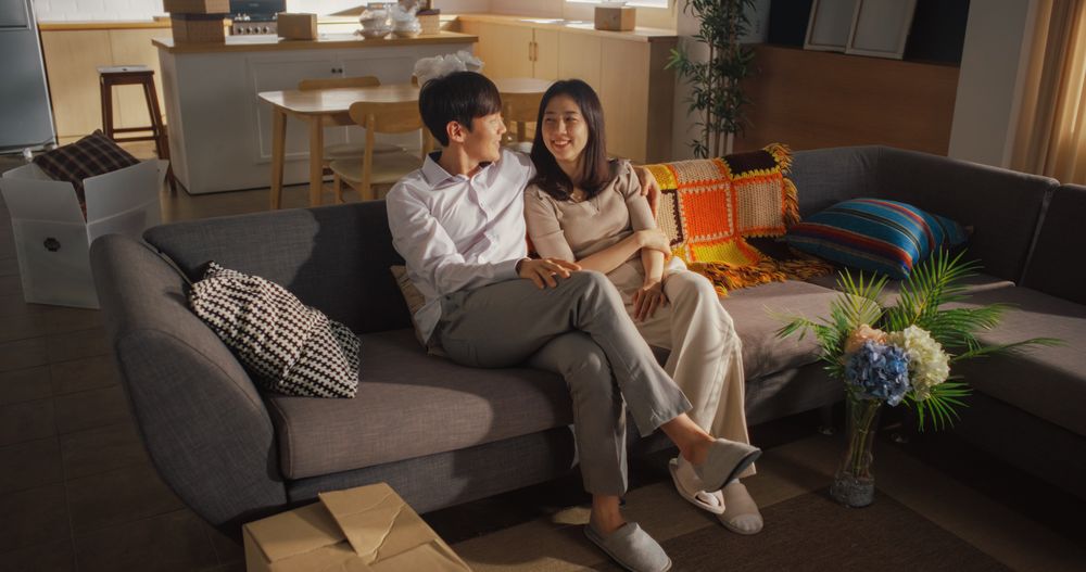 Family Home Moving in: Happy Young Korean Couple Sitting in Newly Purchased Apartment.
