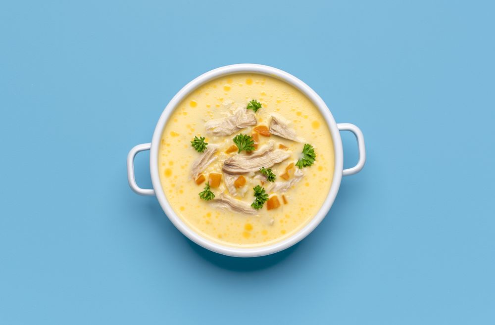 Greek chicken soup avgolemono, above view on a blue background