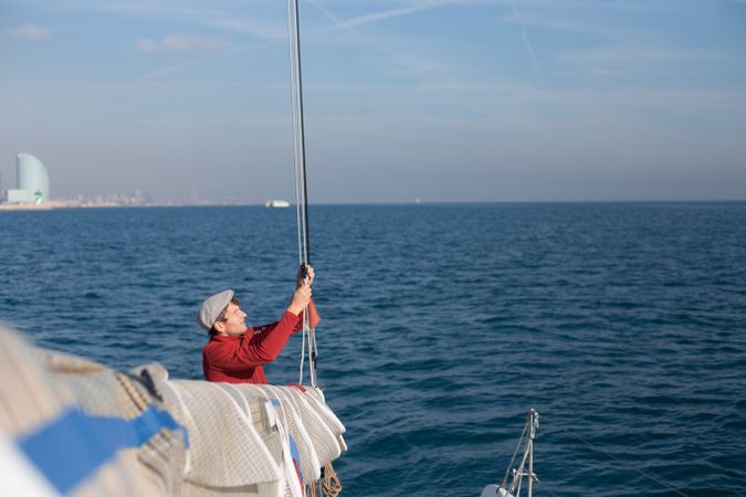 Sailor pulling on cords on sailboat