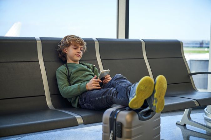 Boy using smartphone while sitting on bench