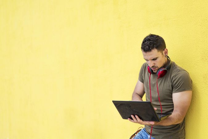 Male with red headphones standing outside with laptop