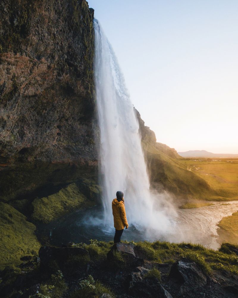 Person standing on rock near waterfalls during daytime