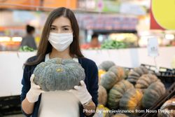 Woman in surgical mask and gloves picking square in produce aisle 4MBDrb