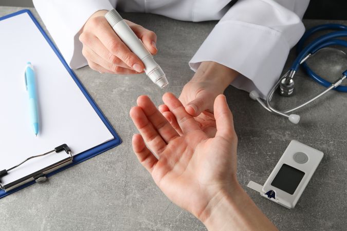 Doctor checking blood sugar level in patient diabetes on gray table