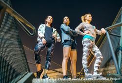 Three women standing on stairs at night ready for an evening exercise session in the city 5kRmZ6