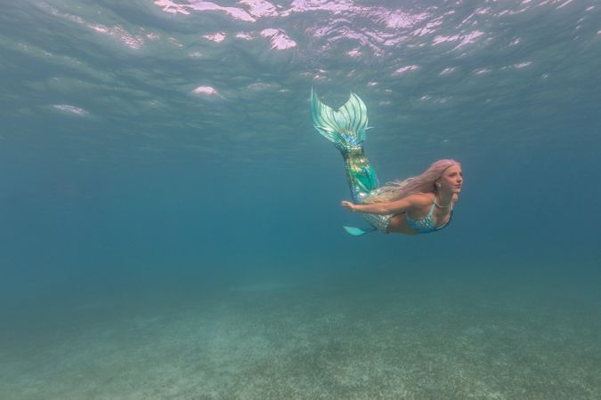 Blond fairytale female mermaid swimming underwater