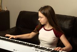 Girl playing the piano, focusing on the keys.