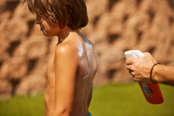 Faceless man applying sun cream on kid