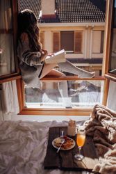 Young woman sitting with tasty drink and book on window
