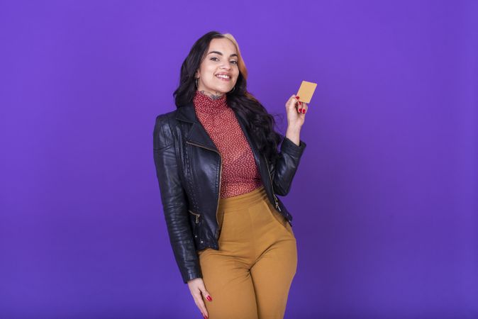 Woman showing a credit card on purple background. Shopping concept.